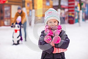 Adorable little girl on skating rink with father