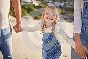 Adorable little girl smiling while walking on the beach with his grandparents and holding hands. Cute caucasian girl