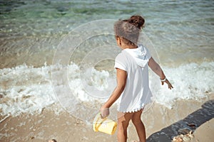 Adorable little girl splashing in tropical shallow water during summer vacation