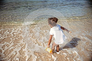 Adorable little girl splashing in tropical shallow water during summer vacation