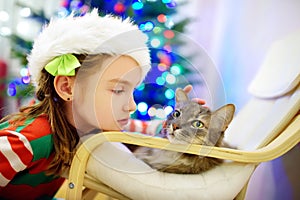 Adorable little girl stroking her cat on Christmas day. Spending time with family and pets on Christmas.