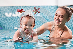 Adorable little girl swimming in pool with mother.