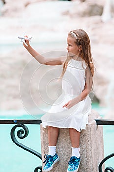 Adorable little girl with toy airplane background Trevi Fountain, Rome, Italy.