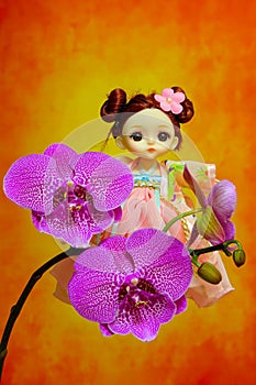 Adorable little girl toy with pink phalaenopsis orchids   