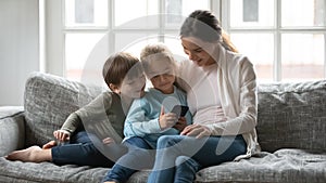 Adorable little girl using telephone applications with brother and mommy.