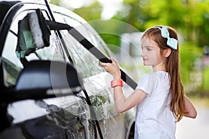 Adorable little girl washing a car on a carwash