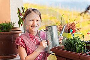 Adorable little girl watering plants on the balcony