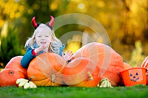 Adorable little girl wearing halloween costume having fun on a pumpkin patch