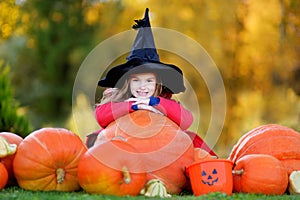 Adorable little girl wearing halloween costume having fun on a pumpkin patch