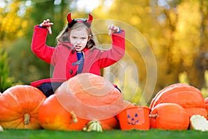 Adorable little girl wearing halloween costume having fun on a pumpkin patch