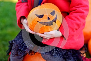 Adorable little girl wearing halloween costume having fun on a pumpkin patch