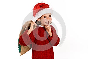 Adorable little girl wearing santa hat carrying gift bag