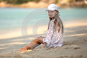 Adorable little girl at white beach during summer vacation,Cute little girl sitting alone on the beach looking at the sea,Travel