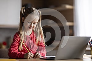 Adorable Little Girl Writing Notes While Study With Laptop At Home