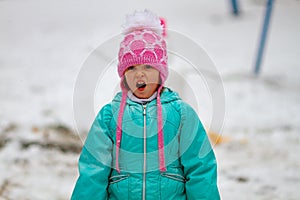 Adorable little girl yawning widely outdoors on a snowy day