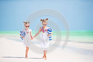 Adorable little girls with beach towels on white tropical beach