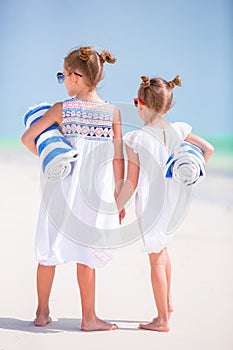 Adorable little girls with beach towels on white tropical beach