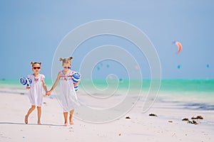 Adorable little girls with beach towels on white tropical beach