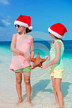 Adorable little girls on Christmas beach vacation. Kids with starfish background the blue sky and turquiose sea