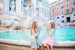 Adorable little girls on the edge of Fountain of Trevi in Rome.