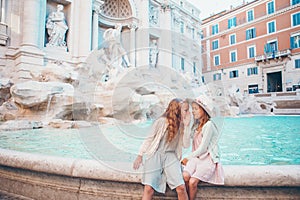 Adorable little girls on the edge of Fountain of Trevi in Rome.