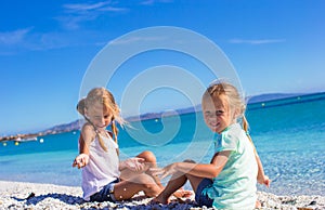 Adorable little girls have fun on white beach