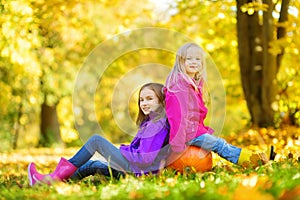 Adorable little girls having fun on a pumpkin patch on beautiful autumn day