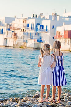 Adorable little girls at Little Venice the most popular tourist area on Mykonos island, Greece. Back view of beautiful