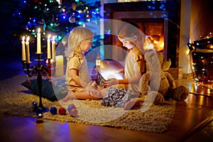 Adorable little girls opening a magical Christmas gift