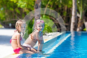 Adorable little girls in outdoor swimming pool on