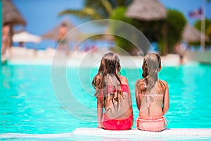 Adorable little girls in outdoor swimming pool on summer vacation