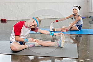 Adorable little girls in sportswear exercising on yoga mats in gym