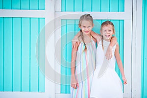 Adorable little girls on summer vacation background traditional colorful caribbean house