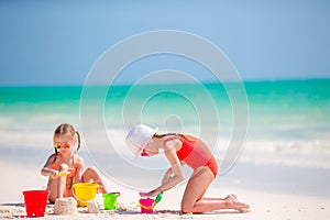Adorable little girls during summer vacation. Kids playing with beach toys on the white beach