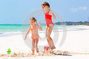 Adorable little girls during summer vacation. Kids playing with beach toys on the white beach