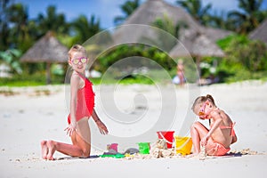 Adorable little girls during summer vacation. Kids playing with beach toys on the white beach