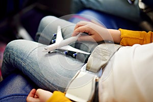 Adorable little girls traveling by an airplane. Children sitting by aircraft window and playing with toy plane.