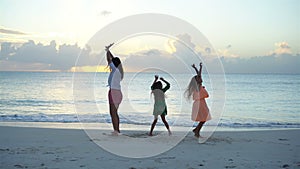 Adorable little girls and young mother having fun on white beach.