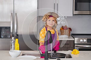 Adorable little helper child housekeeping. Little cute boy sweeping and cleaning dishes at kitchen.