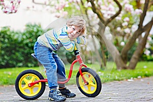 Adorable little kid boy driving his first bike or laufrad