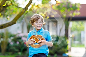 Adorable little kid boy eating huge big bavarian german pretzel.