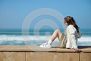 Adorable little kid girl breathing fresh air and enjoying beautiful view of waves pounding on the Atlantic shore