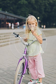 adorable little kid with ice cream and bicycle standing