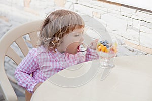 Little girl eating fruit salad.