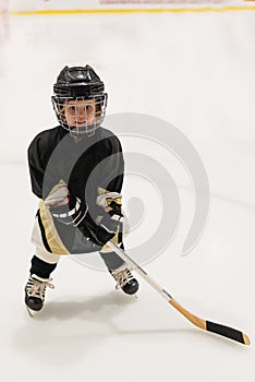 Adorable little kid 3 years-old plays hockey on ice wearing in full hockey equipment