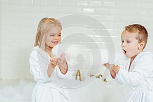 adorable little kids in bathrobes playing with foam