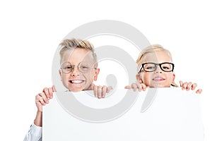 adorable little kids in eyeglasses holding blank banner and smiling at camera