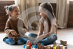 Adorable little kids sisters playing with toys in living room.