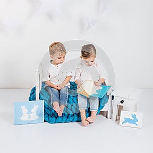 adorable little kids sitting on blue knitted plaid and reading book and rabbit cards