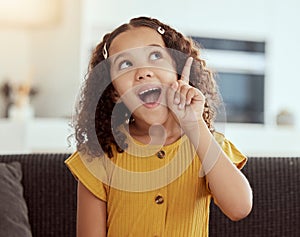 Adorable little mixed race child thinking at home. One small cute hispanic girl sitting alone on a sofa in a living room